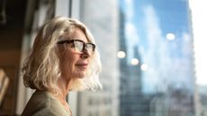 An older woman looks out a window.