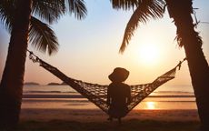 A woman sitting in a hammock on the beach