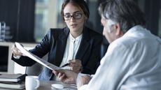 A financial adviser walks an older man through some paperwork in her office.